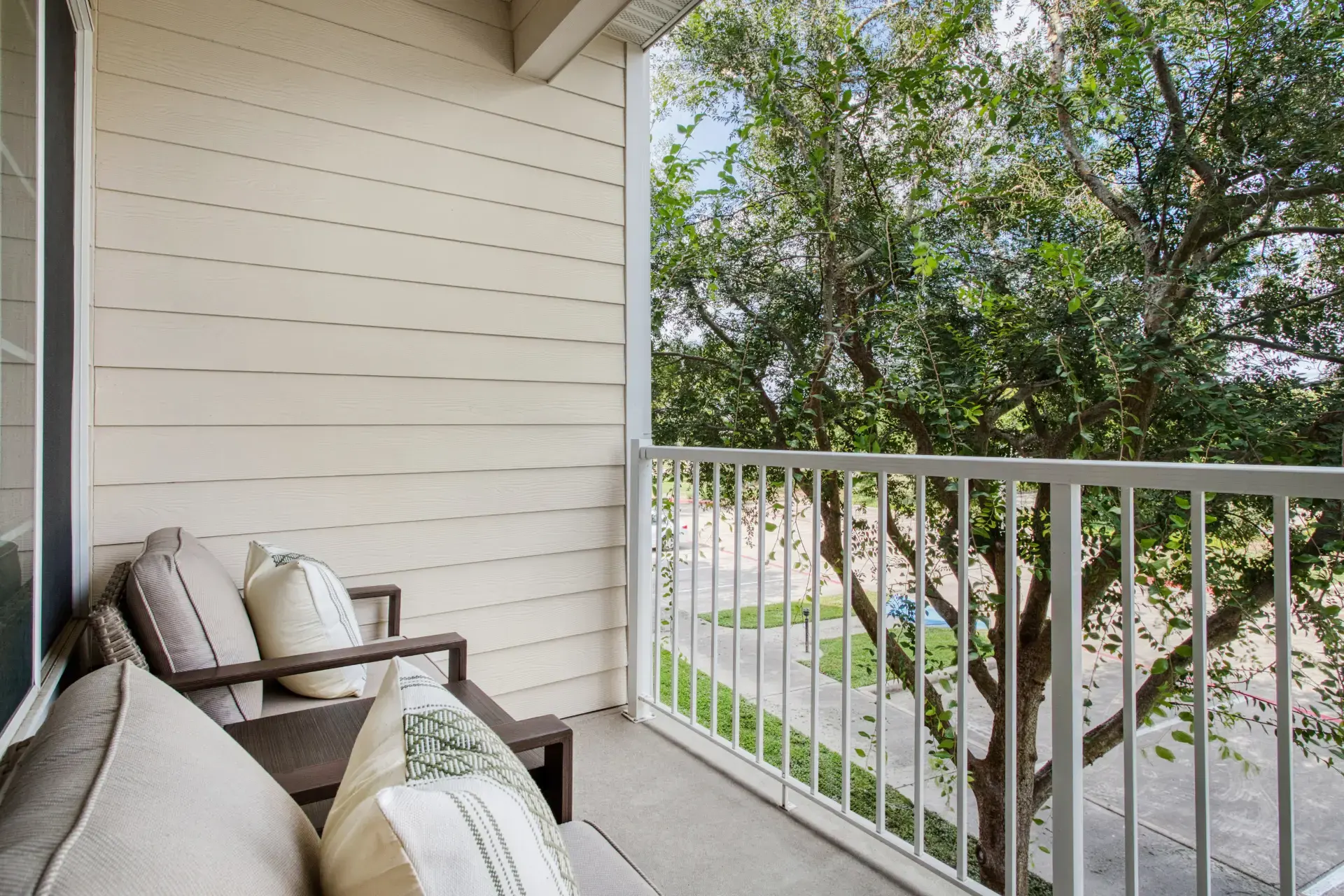 Outdoor seating with pillows with views of trees.
