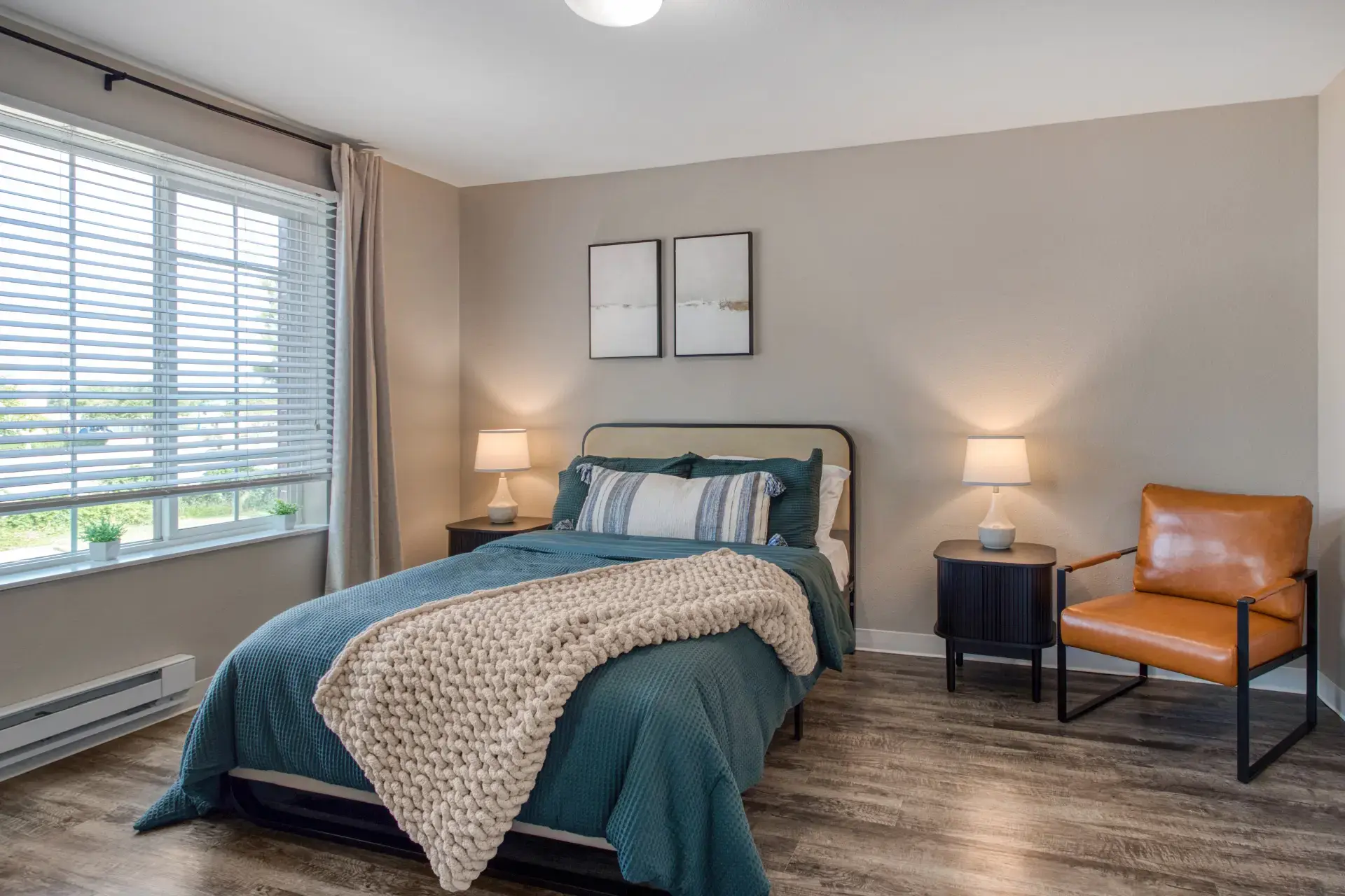 Furnished bedroom with lighting and comfy seating and window with a view.
