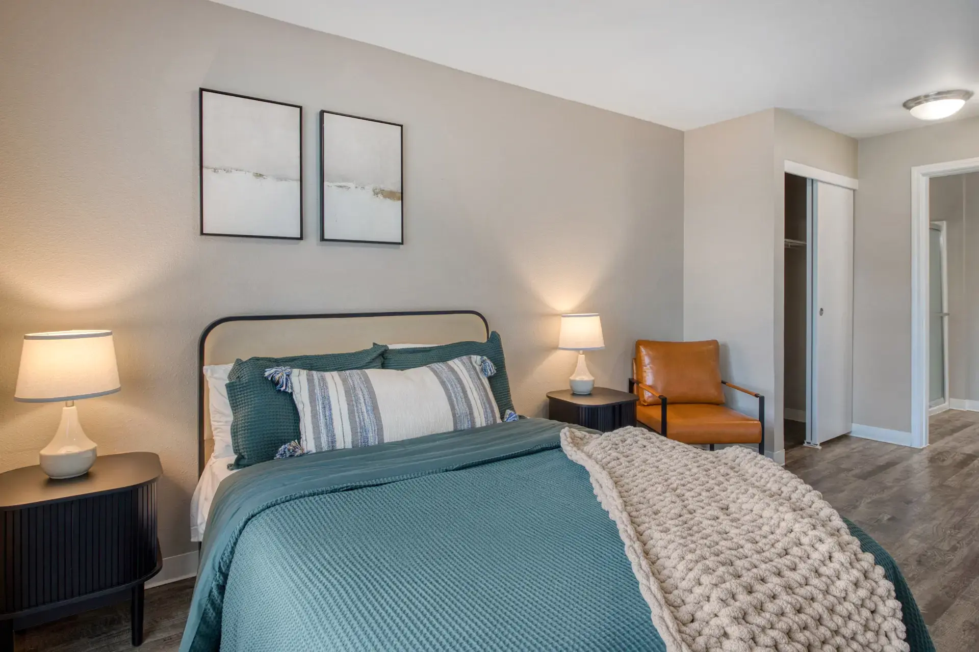 Fully furnished bedroom with lights on and comfy pillows.
